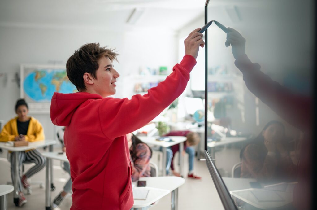 College student explaining some ideas on a touch TV in classroom.