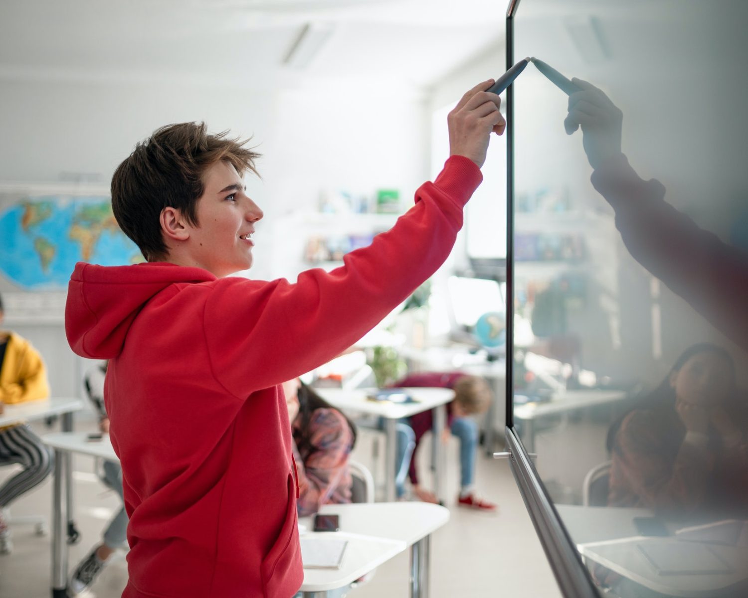 College student explaining some ideas on a touch TV in classroom.