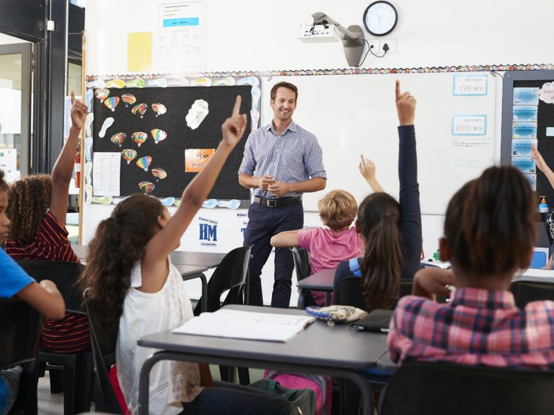 School kids raising hands in elementary school class